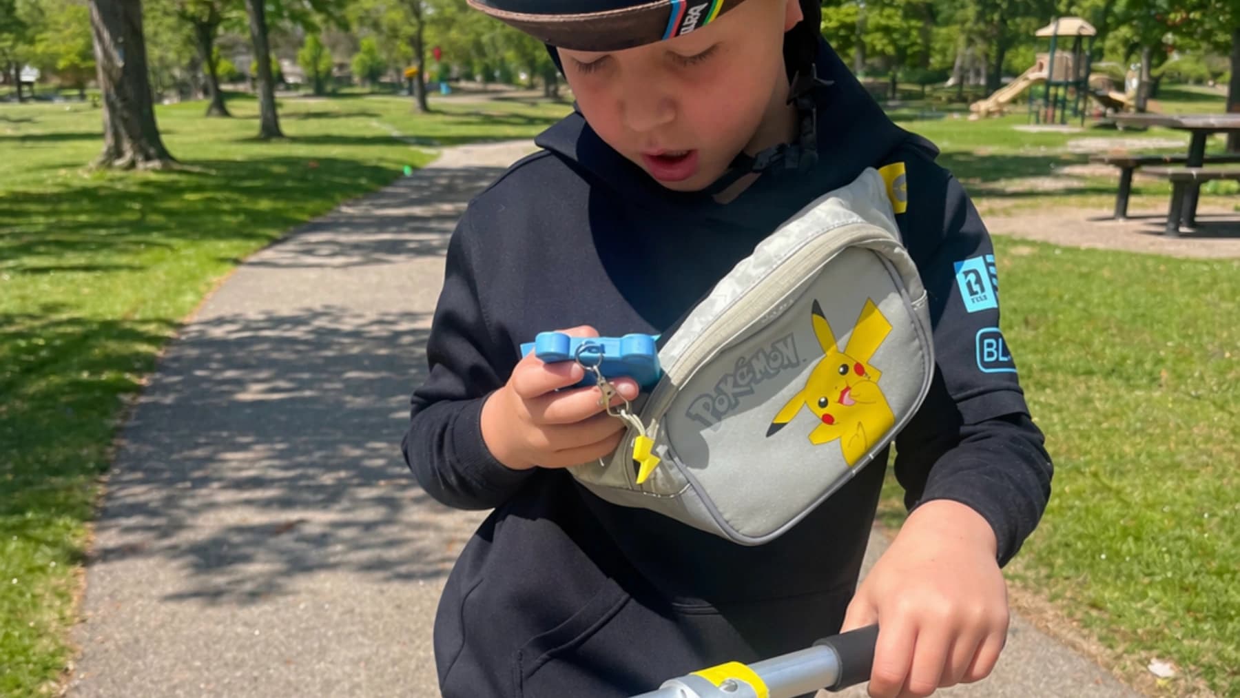 Child using Kiko while riding a scooter in a park